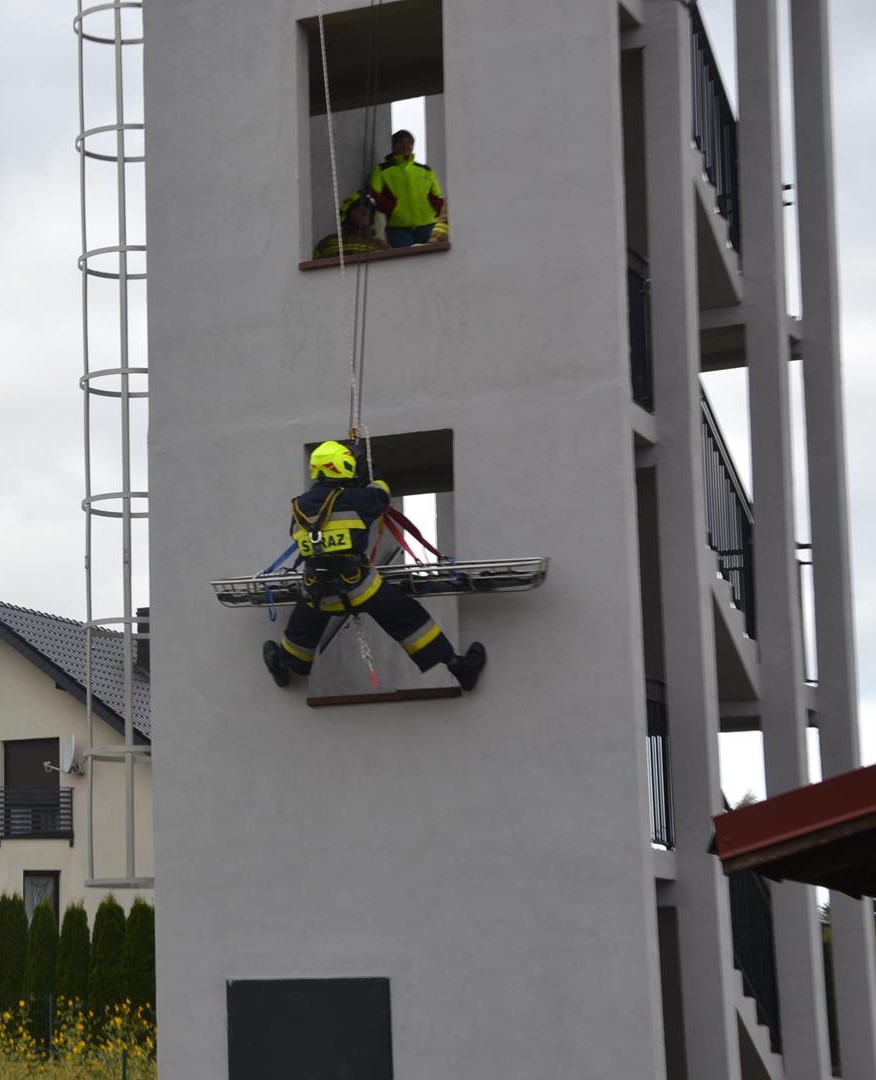Zajęcia wysokościowe 0- ewakuacja poszkodowanego z budynku Strażak podczas zjazdu linowego po ścianie budynku z noszami