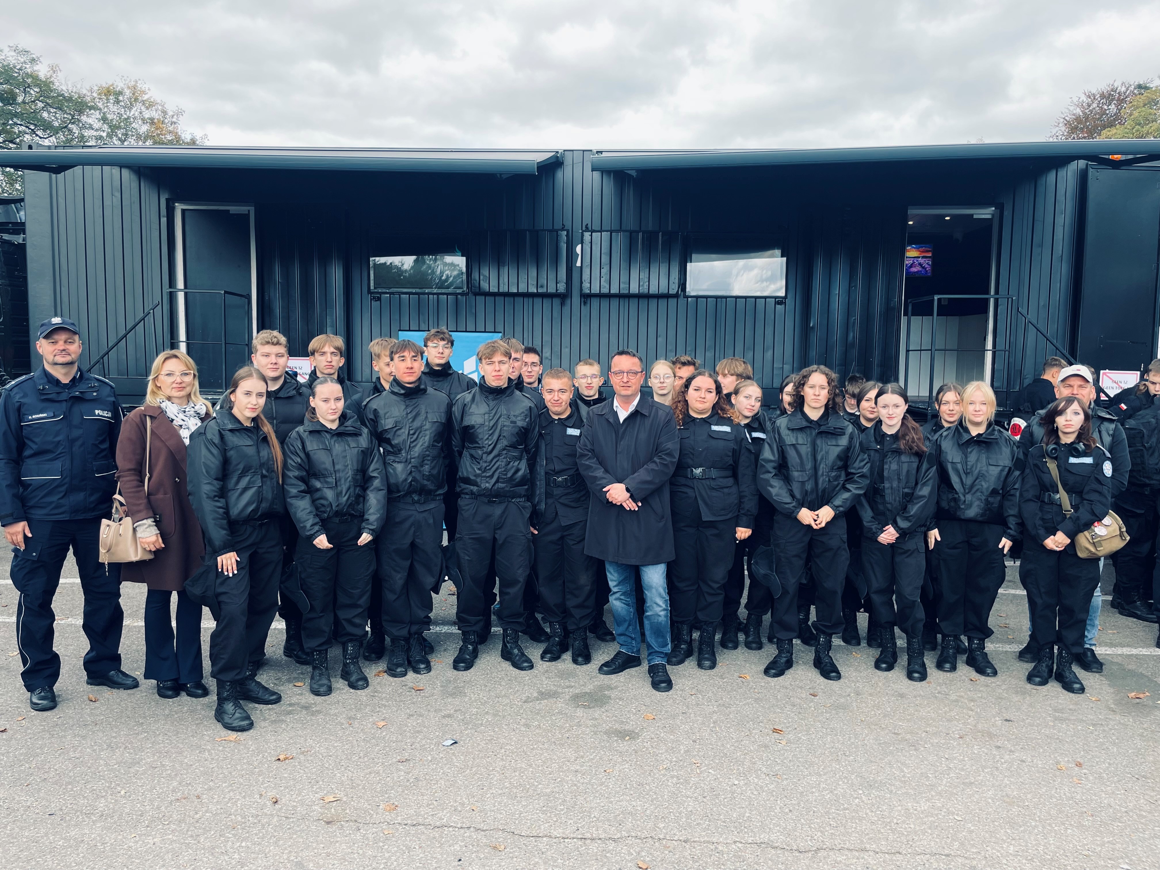 Członek Zarządu Województwa pan Bogdan Jaroszewicz w otoczeniu uczniów klas mundurowych Zdjecie zbiorowe na tle przyczepy edukacyjnej