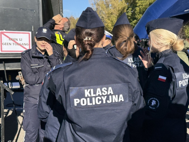 Uczniowie klas mundurowych, na pierwszym planie plecy uczennicy w kurtce z napisem - Klasa Policyjna