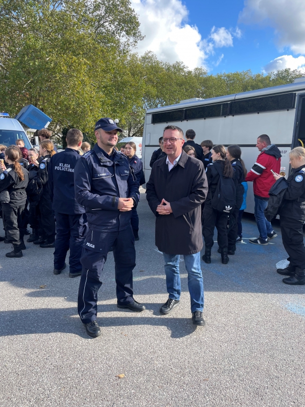 Wicewojewoda i Członek Zarządu Województwa stoją na tle uczniów klasy policyjnej