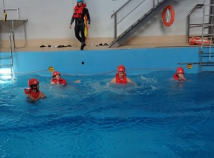 Widok na basen treningowy, w którym unoszą się kursanci w kaskach i kamizelkach ratunkowych