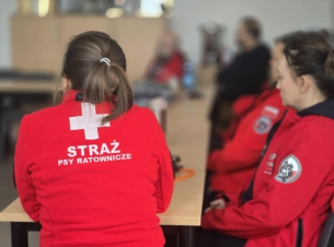 Plecy ratownika- napis Straż- Psy Ratonicze na czerwonej bluzie pożarowej