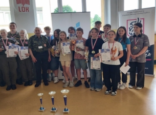 Zdjęcie zbiorowe - zwycięzcy konkursu, na pierwszym planie widoczne puchary.